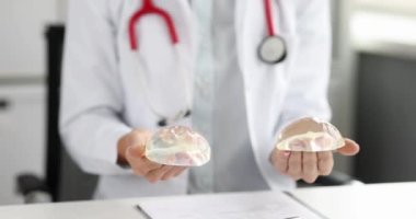 Doktor mamolog elinde silikon implantlar tutuyor. 4K film. Estetik tıp ve estetik cerrahi konsepti