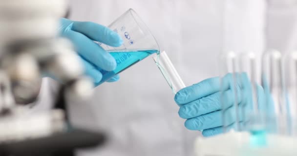 Filminde Eldivenli Kimyager Mavi Sıvıyı Test Tüpünden Test Tüpüne Boşaltıyor — Stok video