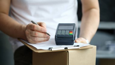 Erkek el yazısı makbuzu, yakın çekim. Kurye ile iyi teslimat ve banka transferiyle ödeme. Terminal, karton kutu ve belge kavramı.