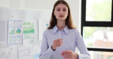 Modern ofisteki iş kadınının portresi, arka plandaki grafiklere karşı. Kadın işçi iş yerinde liderlik ve başarı gösteriyor.