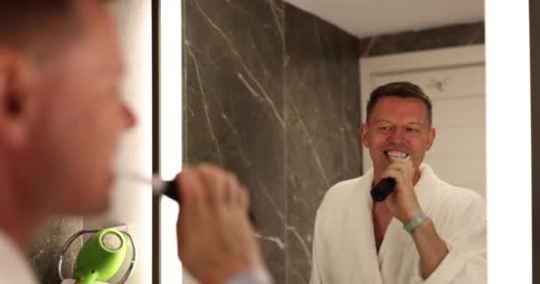 Yakışıklı Bir Adam Aynaya Bakarak Dişlerini Elektrikli Ağız Sulama Makinesiyle — Stok video