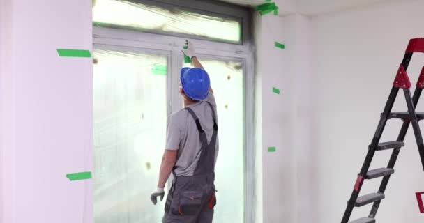 ビルダーは白いスプレーのペンキが付いているポリ塩化ビニールの窓の層を塗ります 汎用修理スプレーペイント — ストック動画