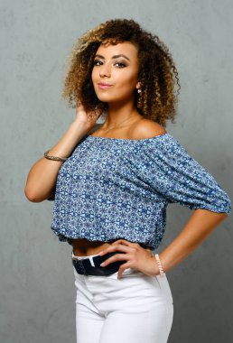 Güzel siyah kadın portre. Bir gri arka plan ve gülümseyen güzellik moda stil kıvırcık saçlı beyaz lifler görünüm göz kamera ile değer