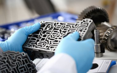 Otomatik vites kutusundaki tamirci elinde mavi koruyucu eldivenler tutuyor. Hidroblok detayı tanı koymayı kurutur ve detaylı test iletimini yakınlaştırır.