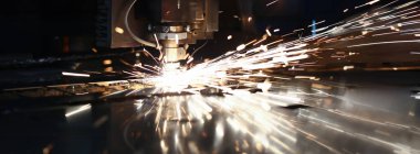 Metalurjik bitki arka planında metal işleme lazer metali için makineden çıkan kıvılcımlar. Otomotiv üretim kavramı için tamamlanmış parçalar üretiliyor