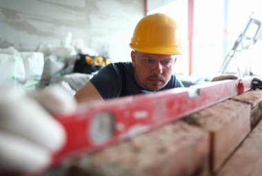 Akıllı erkek portresi inşaat yöntemi düzeyinde belirli kalitede kalmak için özel ekipman kullanarak. Sakallı inşaatçı, elleri zarar görmeden tutmak için sert eldivenler giyiyor. Bina konsepti