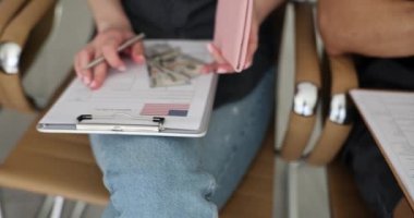 İnsanlar seyahat vize başvuru formunu Amerikan bayrağıyla dolduruyor. Pasaportu olan bir kadın bekleme odasındaki sandalyede oturuyor.