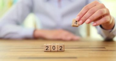 Kadın eli, yeni yıla başlama beklentisi içinde 4 numaralı ahşap küpü yerleştirdi. Yeni yılın başlangıcına hazırlık yavaş çekimde yeni hedefler