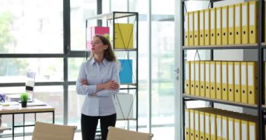 Ofiste yürüyen sinirli bir iş kadını. Ofis çalışanı kollarını gergin ve yoğun ifadeyle ağır çekimde kavuşturur.