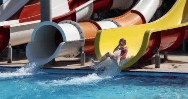 Mayo giyen kız, güneşli bir havada su parkındaki havuza uçuyor. Aktif yaşam tarzı ve eğlence anlayışı yavaş çekim