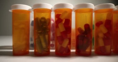 Turuncu ve şeffaf şişeler, çok renkli kapsüllerle beyaz masanın üzerinde sıralanır. Hafif çekimde sağlıklı vücut için çeşitli beslenme malzemeleri.