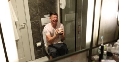 Erkek, tuvalette kaka yaparken acı çektiği için çok zorlar. Adam tuvalet kağıdını elinde tutuyor. Sindirim sorunları ve günlük banyo tedavisi yavaş çekimde.