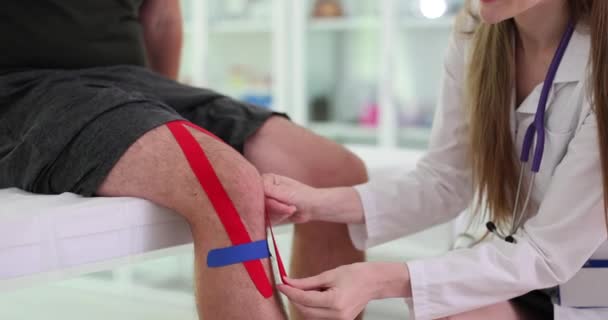 Orvos Kineziológiai Ragasztószalagot Alkalmaz Férfi Beteg Térdízületére Csökkenti Duzzanatot Fájdalmat — Stock videók