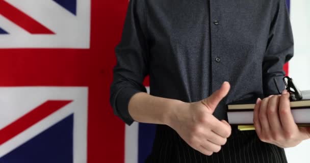 英语老师拿着书本和眼镜站在英国国旗的后面 露出大拇指 语言学习和专家慢动作的认可 — 图库视频影像