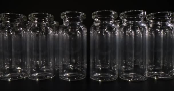 ワクチンのための空のガラス瓶は ダークスタジオの表面上の列に立っています 医療目的および実験室調査のための専門のガラス器は動きを遅らせます — ストック動画