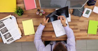 Erkek doktor, özel klinikteki hastanın röntgen görüntüsüne bakıyor. Steteskopta uzman biri teşhis koymak için resmi inceliyor.