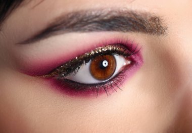 Model büyüleyici gözün yakın çekimi. Bordo renklerinde, altın parıltılı profesyonel makyaj. Mükemmel kaş şekli. Akşam maquillage sanatı. Güzellik ve kozmetik konsepti