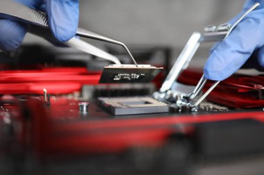 Yakın plan eldivenli eller mikroçip detaylarını onarıyor. Mikroişlemci tabanlı endüstriyel cihazlar test ediliyor. Arıza tespiti ve cihaz onarımı. Kurtarma sürücüsü. Mikroişlemci koruma tasarımı