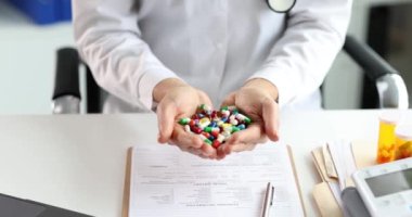 Kadın doktor, klinikte elinde birçok renkli kapsül tutuyor. Ağır çekimde. Tıbbi ürünler konsepti