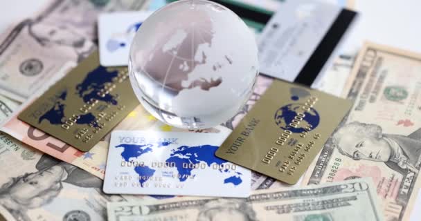 Glaskugel Liegt Auf Plastikkreditkarten Und Dollarscheinen Film Zeitlupe Weltfinanzmarktkonzept — Stockvideo