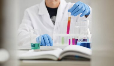 Erkek bir kimyager elinde cam test tüpü tutarak potasyum permanganatın sıvı çözeltisini taşır. Kimyasal imalatı kullanarak çeşitli reaksiyonlar uygular.