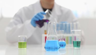 Erkek bir kimyager elinde cam test tüpü tutar ve potasyum sıvısı taşar. Permanganat bir analiz reaksiyonu yapar. Kimyasal imalat kullanarak çeşitli reaksiyonlar uygular.