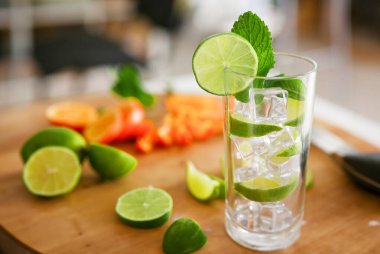 Votka yaprağı naneli mojito kokteyli ve derisi yüzülmüş mutfak arka planındaki bar ürünleri için limonlu bira baskısı. Moda mobilyalar, siyah gri eğimli dilimlenmiş meyve ve buz..