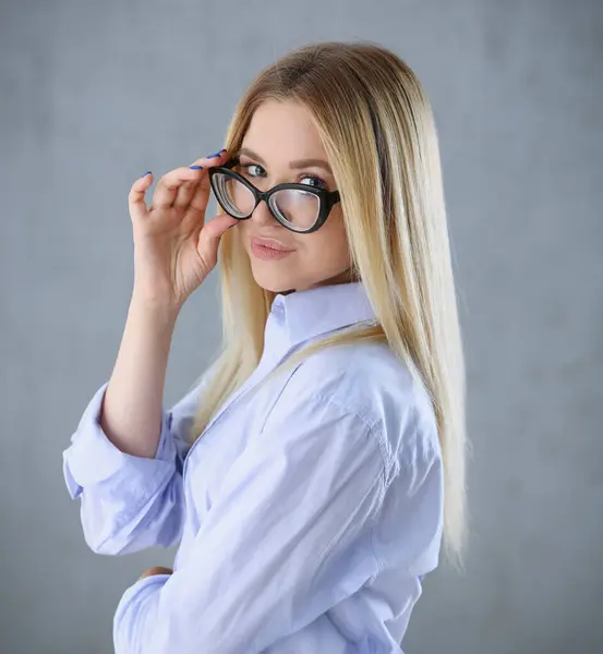 Portrait of a sexy woman in a mans shirt wearing glasses on a gray background looks at the camera. Smiling look advice to give wants objections are not accepted.