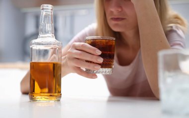 Drunk woman holding glass of whiskey and alcoholics alone. Unhappy woman suffering from migraine depression disease and anxiety