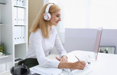 Güzel kız öğrencinin öğrenme ve müzik kulaklık ile. Kalem elini ve laptop monitör arıyor tutun