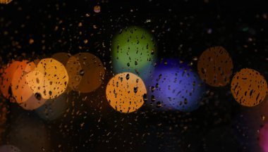 Cam üzerine şehir yağmur damlaları gece arka plan bulanık