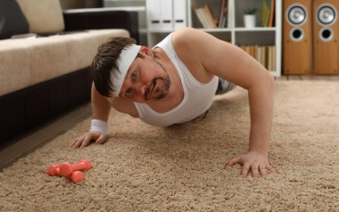 Aşırı kilolu genç yakışıklı bir adam evdeki ilk spor salonunu halıda yapıyor. Sersemlemiş ve aşırı yüklü olması kilo vermeye teşvik etmiyor..