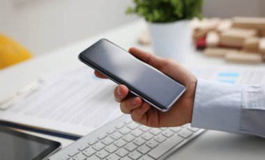 Bir iş adamı elinde yeni bir akıllı telefon tutar. Mobil uygulama pazarı vitrini gösterir. Reklamcılık veya finansal istatistikler için resminizi ekleyebilirsiniz.