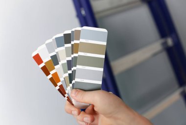 Tasarımcı pantone renk Kılavuzu hayranıyım elinde tutar. Duvarlar daire dağıtım promosyon kavramı sırasında renk için renk seçenekleri