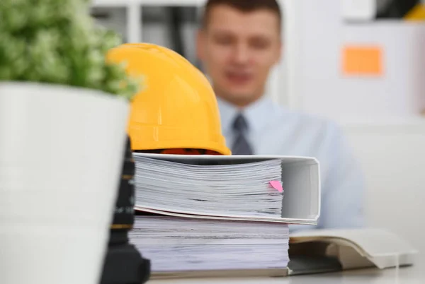 Businessman engeneer architect in office on a background of yellow office and folders with papers