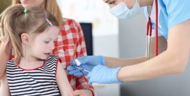 Pediyatrist doktor omzundaki küçük kızı aşıladı. Alerjik hastalıklı çocukların aşılanması konsepti