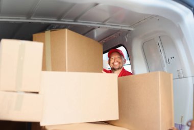 Gülümseyen erkek kurye arabadan karton kutu çıkarır. Lojistik taşımacılık uluslararası ulaşım kavramı