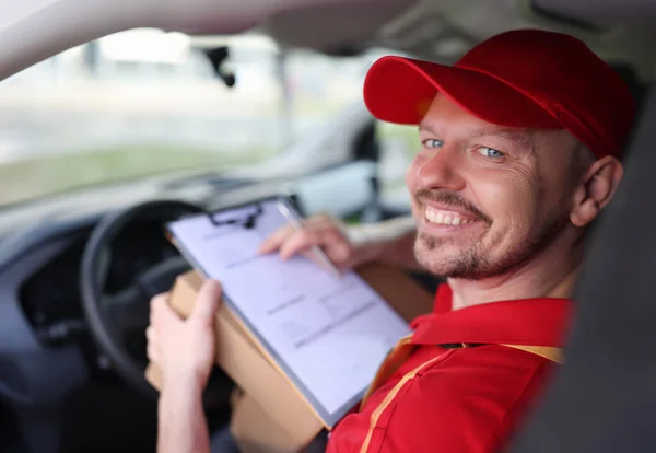 Portrait of smiling male courier driver in car salon with documents. Logistic transportation service concept