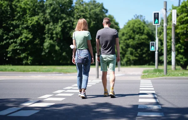 Kadın ve erkek yaya geçidinden karşıya geçiyorlar. Yaya güvenliği ve yol konseptine bakım