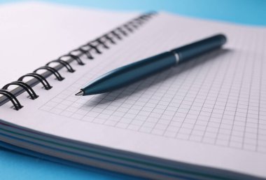 Masanın üzerinde kalem olan boş beyaz bir defter. Öğrenim ve eğitim kavramı