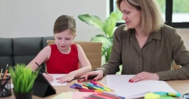 Çekici genç anne ve kız renkli kalemlerle kağıda resimler çiziyor. Sevgi dolu aile iletişimden ve ortak yaratıcı hobiden hoşlanır.