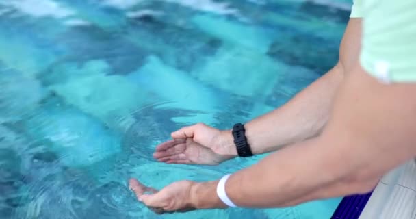 新鮮で清潔な水が人の手のひらに流れ込んでいる プールの端に手を伸ばした人 — ストック動画