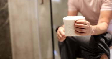 Adam tuvalet kağıdıyla tuvalette oturuyor ve ishal kabızlığından muzdarip. Karın ağrısı ya da krampı olan biri.
