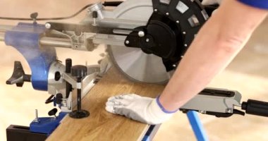 Profesyonel işçiler elektrikli testere ile tahta kesiyor ve yeni lamine ahşap döşemeler yapıyorlar. Zemin kaplaması