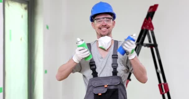 快乐的主修理工用绿色和蓝色瓶子喷雾干燥的喷雾器喷涂白色油漆 修理和油漆 — 图库视频影像