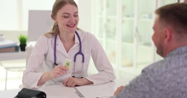男性患者にプラスチックボトルに薬を投与する女性一般開業医 病気の患者の遅い動きのための処方箋を書く家族の医者 — ストック動画