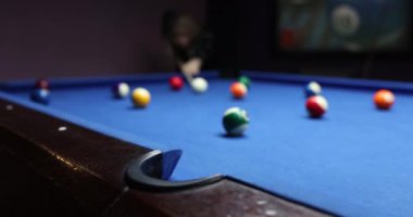 Oyuncu mavi bilardo masasında renkli bilardo toplarını tekmeliyor. Kumarhane kulübünde zaman geçirmek için bilardo oynayan insanlar.