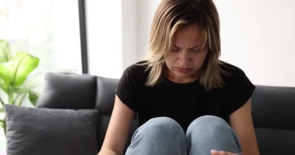 悲伤的年轻女子坐在舒适的沙发上 舒舒服服地躺在宽敞的公寓里 在宽敞的公寓里表现出失望表情的金发女人 — 图库视频影像