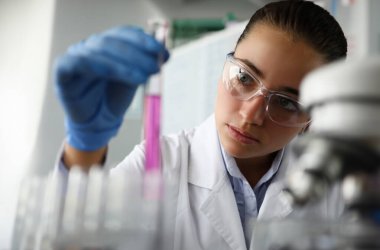 Laboratuvardaki kadın bilim adamı elinde mor sıvıyla test tüpünü tutuyor. İnsan DNA araştırma testi ve klonlama