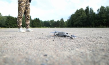 Yerdeki modern gri helikoptere odaklan. Haki pantolonlu adam kontrol ediyor. Profesyonel insansız hava aracı, kamera ile başlamaya hazırlanıyor. Özel mülk ya da askeri nesneleri izlemek için havalan